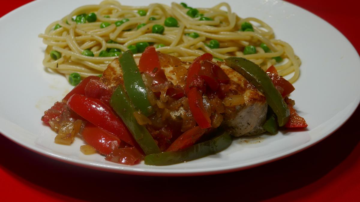 Pork chops Basque style with spaghetti and peas.