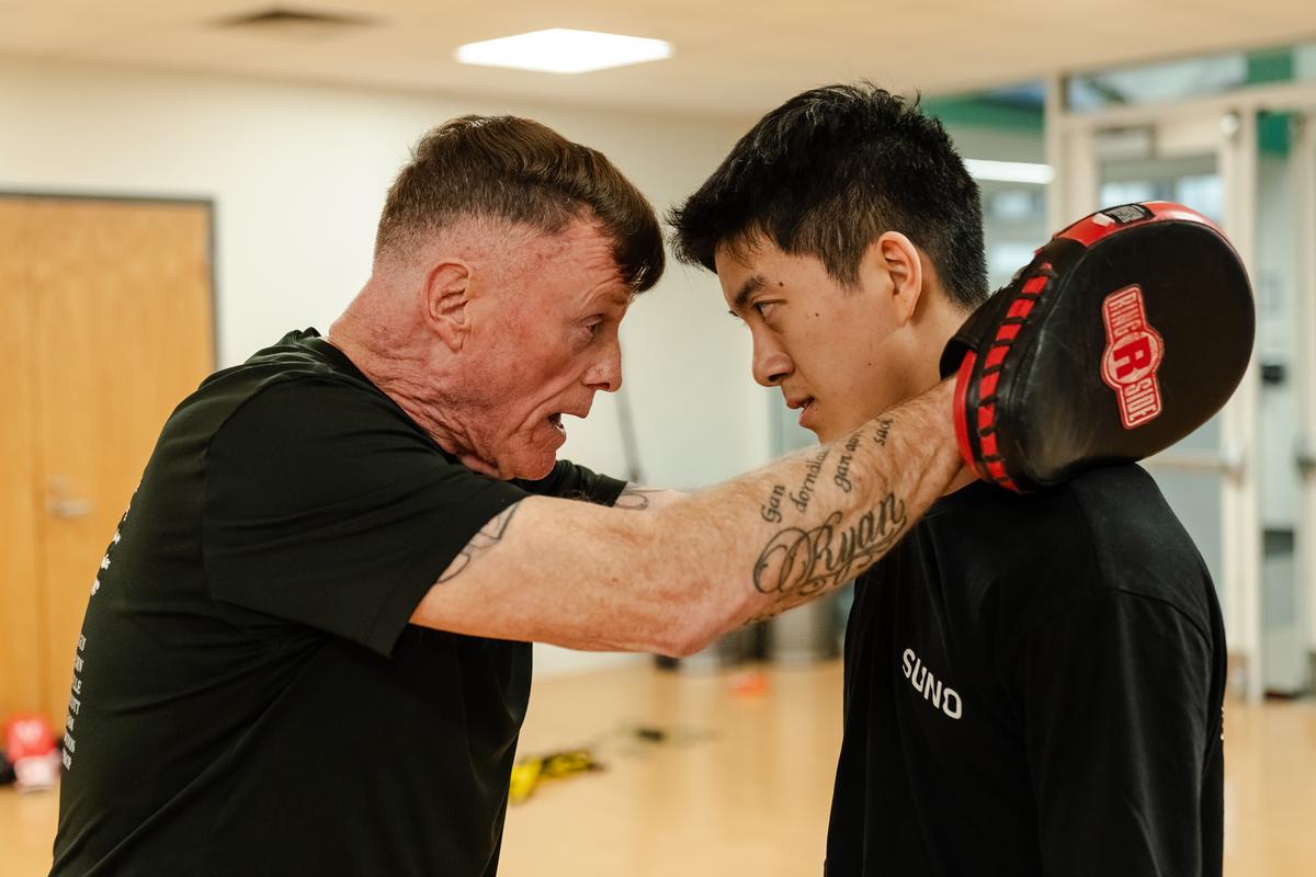 Harvard Boxing Club coach Joe Lake gives a pep talk to freshman Ryan Jiang before a bout during a boxing exhibition at Babson College in Wellesley, Mass., April 24, 2026. Boxing clubs at Harvard and other colleges are drawing new members as students look for a real-life connection. (Sophie Park/The New York Times)