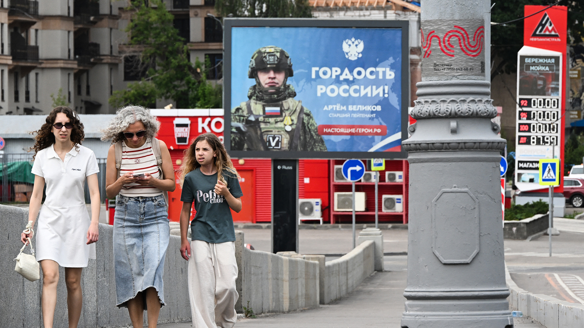 People walk in front of a billboard honoring a participant in Russia's military action in Ukraine and reading "Pride of Russia!" and a Neftmagistral gas station pylon which shows that there is no gasoline at the station in Moscow on July 10, 2026. Russia — one of the world's largest oil producers — has introduced a swath of restrictions on petrol sales across the country, as Ukrainian strikes on its refineries, depots and logistics crimp domestic supply. Several regions have introduced rationing, while some gas stations and chains have sold out or closed due to a lack of supplies. (Igor Ivanko/AFP via Getty Images/TNS)