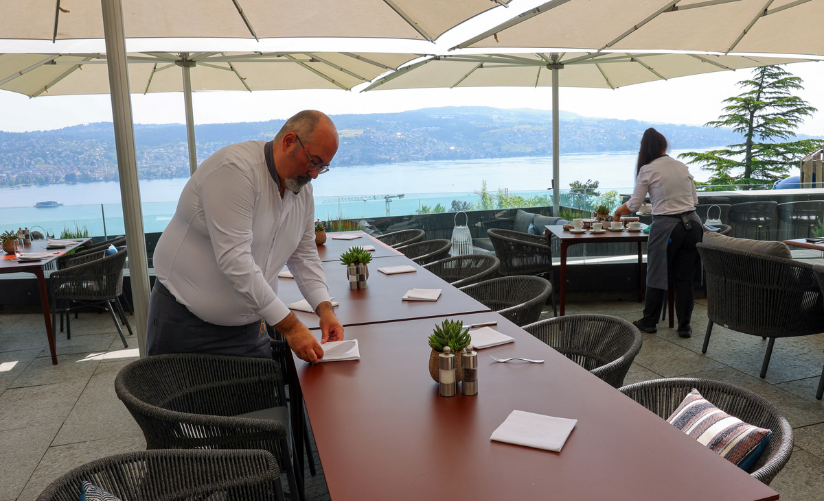 Hotel Belvoir staff members set tables on a terrace overlooking Lake Zurich, ahead of a June 14 vote on a plan backed by the right‑wing party to limit population growth to 10 million inhabitants, in Ruschlikon, Switzerland, May 27, 2026. REUTERS/Denis Balibouse