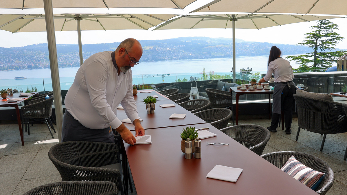 Hotel Belvoir staff members set tables on a terrace overlooking Lake Zurich, ahead of a June 14 vote on a plan backed by the right‑wing party to limit population growth to 10 million inhabitants, in Ruschlikon, Switzerland, May 27, 2026. REUTERS/Denis Balibouse