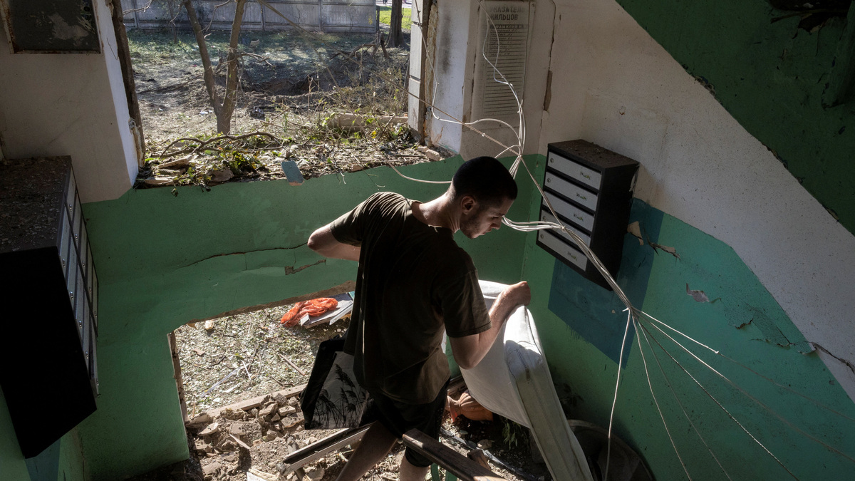 A man carries belongings from an apartment building after it was damaged during a night of Russian missile and drone strikes, amid Russia's attack on Ukraine, in Kyiv, Ukraine, July 2, 2026. REUTERS/Thomas Peter