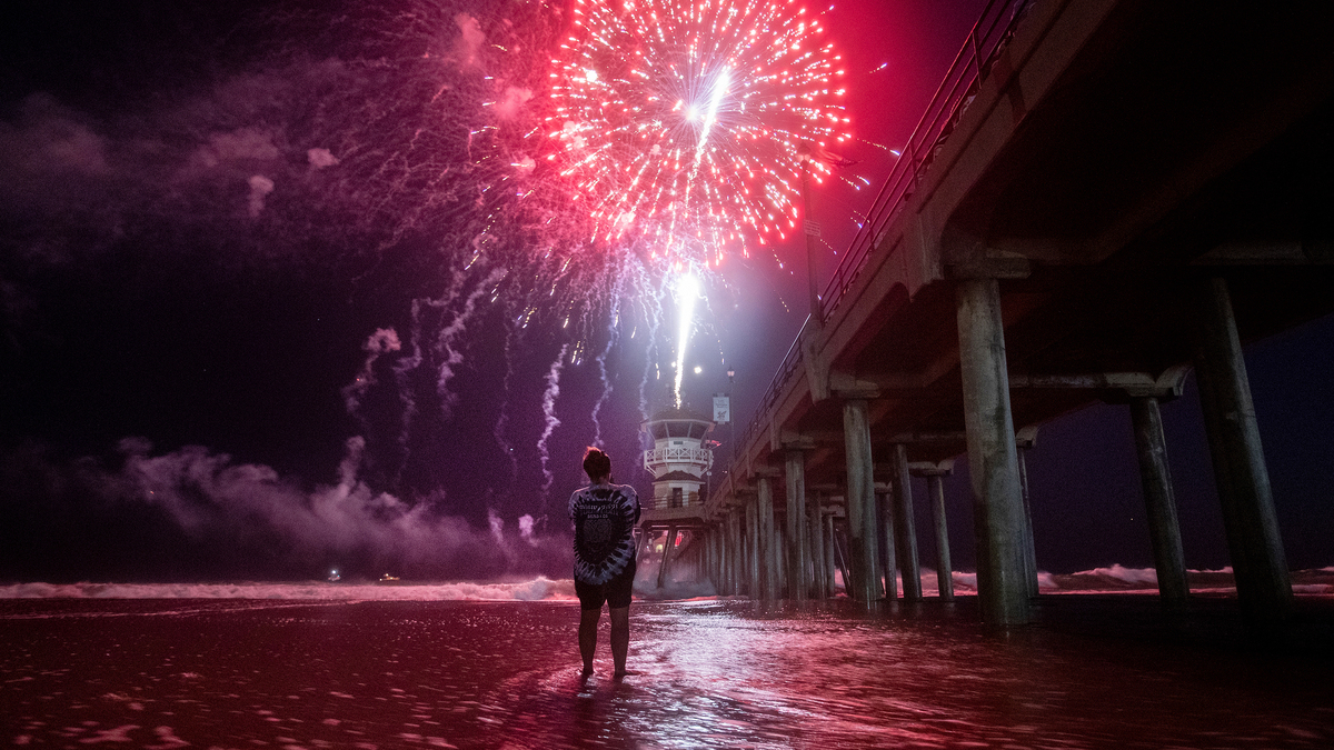 A person wades into the high tide surge to get a closer look at the fireworks celebration over the ocean at the pier in Huntington Beach, California on July 4, 2023. (Allen J. Schaben/Los Angeles Times/TNS)