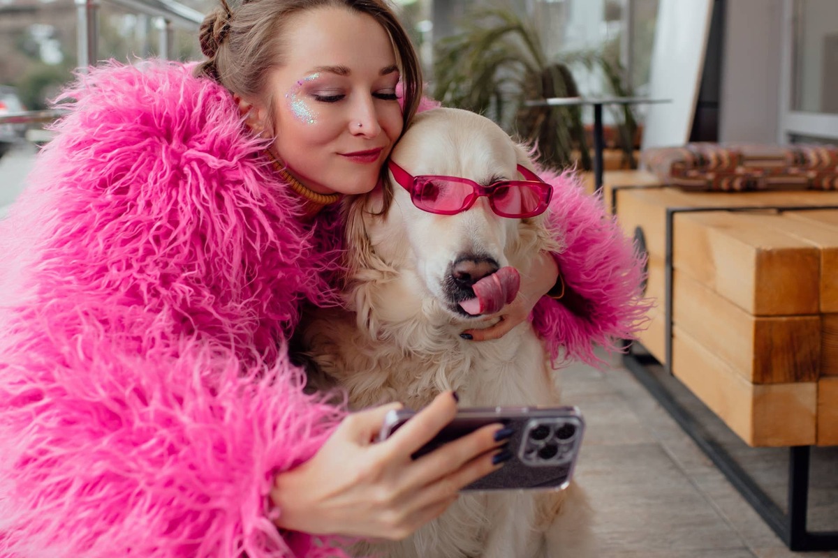  A woman takes a selfie with a Golden Retriever who's sporting sunglasses.