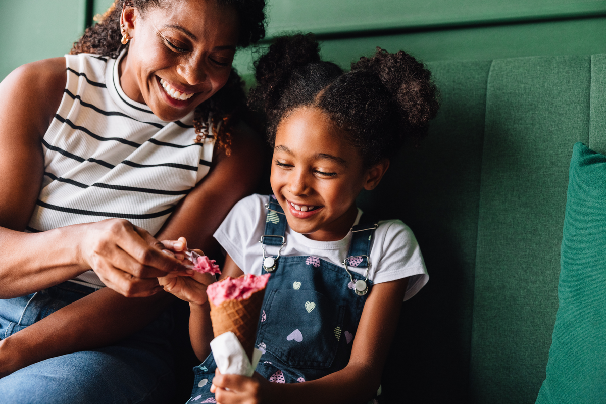  A stock photo of a joyful mother and her young daughter sharing ice cream. 