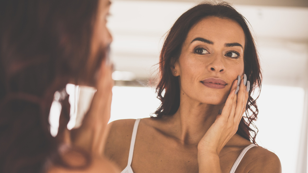 Portrait of a beautiful woman doing her everyday beauty routine in front of mirror.