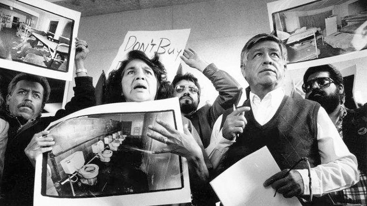 United Farm Workers leaders Dolores Huerta and Cesar Chavez display photos of the conditions that farmworkers endure in San Joaquin Valley farm labor camps at a news conference outside U.S. District Court in Fresno, California, on Nov. 21, 1989. Many in the farmworker community say they are stunned at the revelations alleging that Chavez abused girls and sexually assaulted Huerta decades ago.