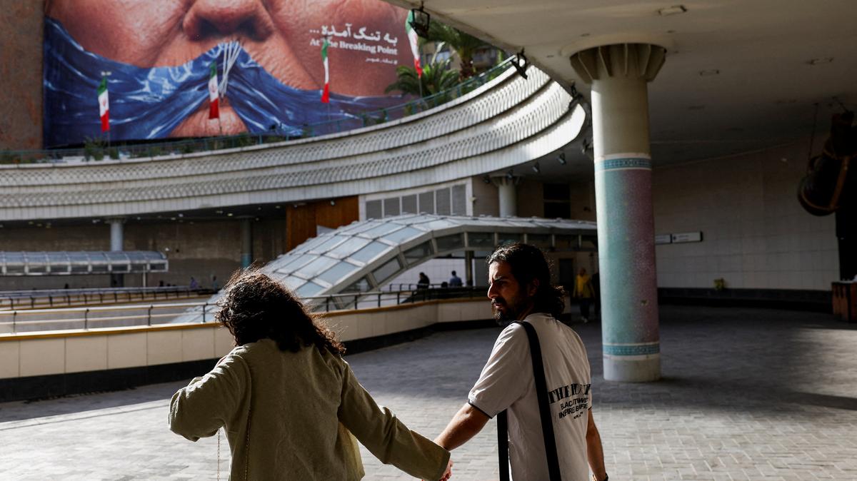 People walk past an anti-U.S. billboard depicting President Donald Trump and the Strait of Hormuz in Tehran, Iran, on May 17. Trump finds himself in a bind as he seeks to end the war against Iran: He is under pressure to reopen the Strait of Hormuz and get U.S. gasoline prices down, but at the same time faces a potential backlash from Iran hawks in his own party over any concessions to Tehran.