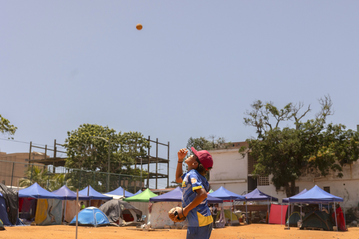 Yeferson Seijas, a 12-year-old center fielder, practices baseball on his old field, which has been converted into a shelter for people displaced by the earthquakes, in La Guaira, Venezuela, on July 1, 2026. His family, like others, is debating whether to move after losing everything, but has so far stayed put to give Seijas a shot at achieving his dream: playing in the major leagues. (Fabiola Ferrero/The New York Times)