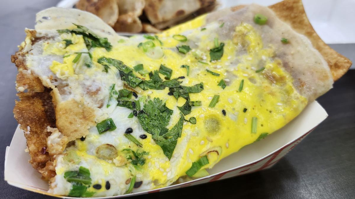 Jianbing, a fresh, warm crepe made from egg, scallions, cilantro and mung bean flour batter, is stuffed with a crispy fried dough stick and topped with savory sauces like sweet bean paste and fermented tofu sauce. It is one of China's most popular street foods and the signature item at TT Crepes, located inside Mei's Supermarket on E. Colonial Drive in Orlando. (Amy Drew Thompson/Orlando Sentinel)