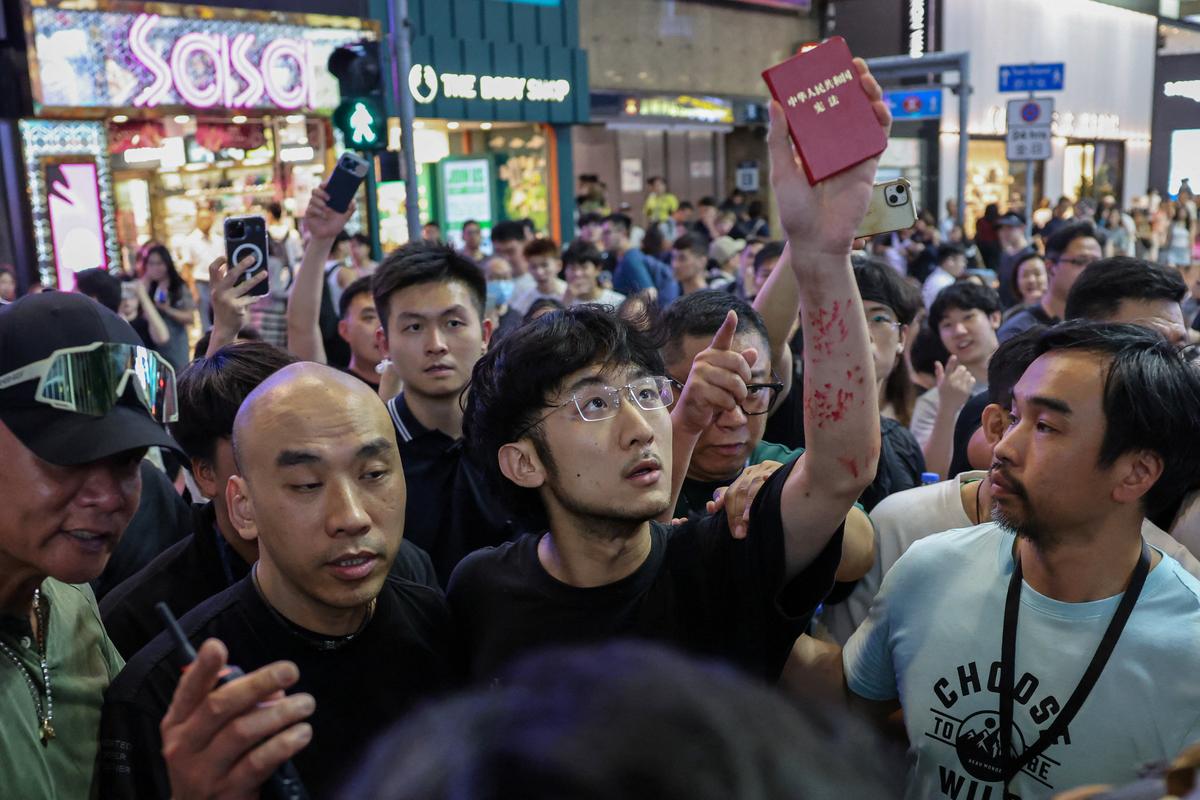 Plainclothes police detain a man holding a book of Chinese Constitution as he performs near Victoria Park, the historic site of annual candlelight vigils commemorating the 1989 Tiananmen Square crackdown, in Hong Kong, China, June 4, 2026. REUTERS/Tyrone Siu