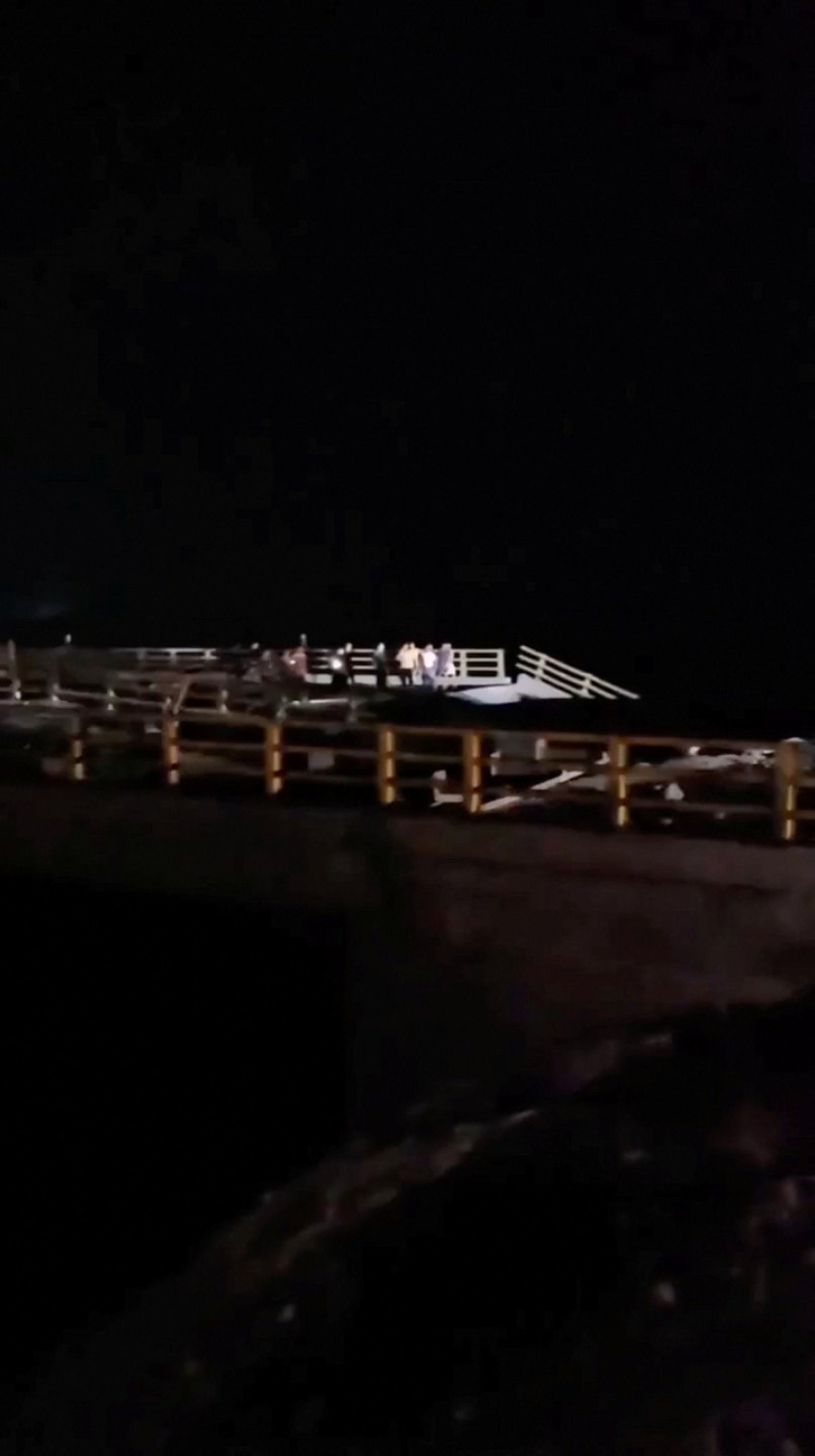 People stand near a damaged portion of a bridge in the aftermath of a strike, in Bandar Khamir, Hormozgan province, Iran July 16, 2026 in this screen grab obtained from social media video. Social Media/via REUTERS