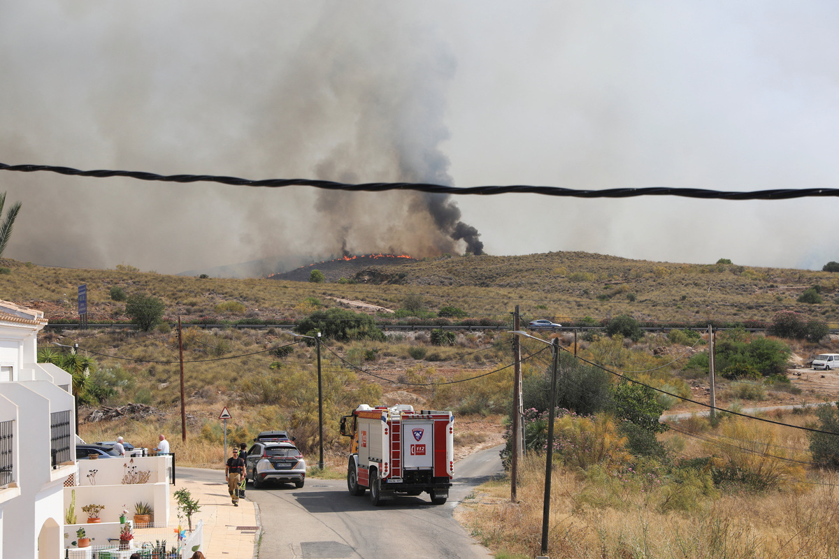A firefighting vehicle stands next to a Spanish Civil Guard vehicle as residents get ready to leave their homes while smoke and flames rise during a wildfire in Los Gallardos, Almeria, Spain, July 10, 2026. REUTERS/Loyola Perez de Villegas Muniz