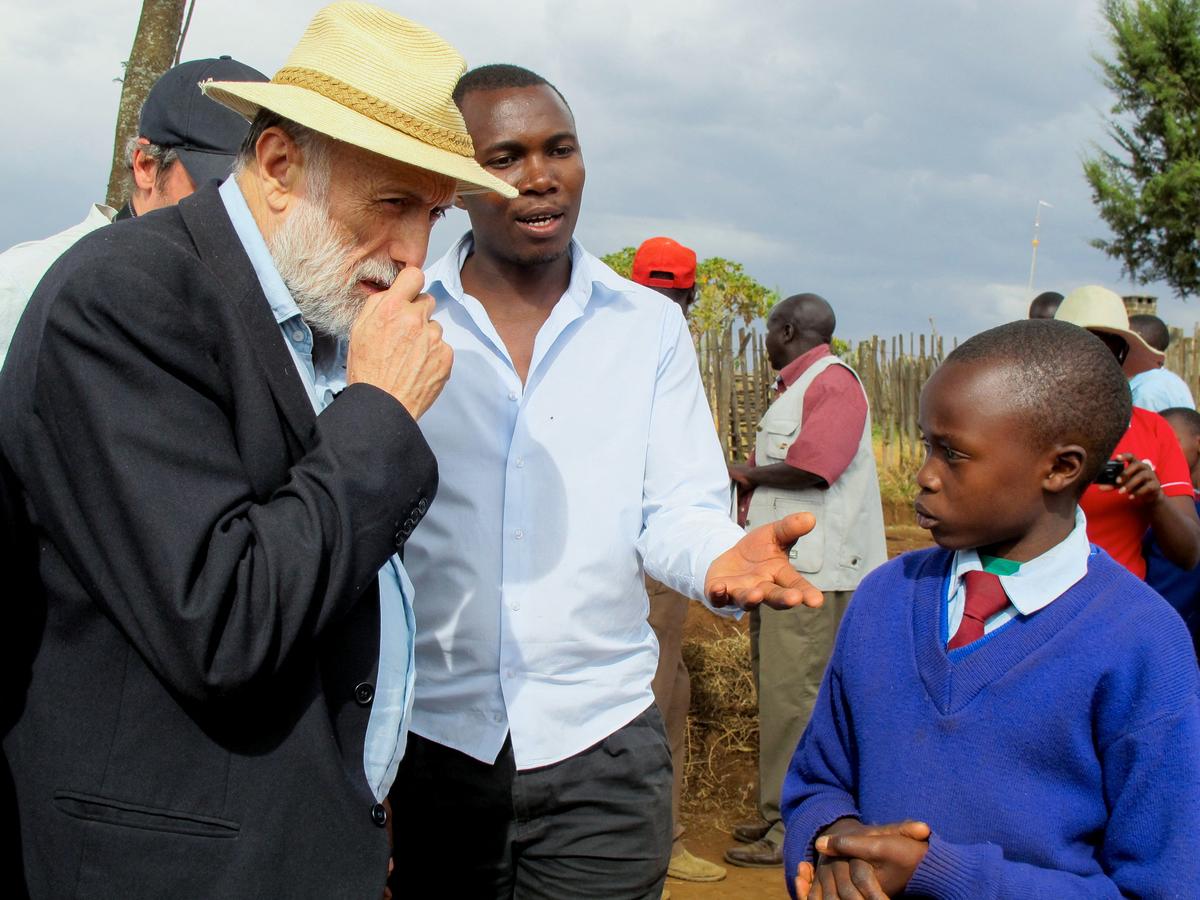 Carlo Petrini, founder of the Italian ‘Slow Food’ movement that promotes quality food, genuine ingredients and local produce, speaks with a schoolchild during a visit to an unknown location in this undated handout picture. SLOW FOOD/Handout via REUTERS