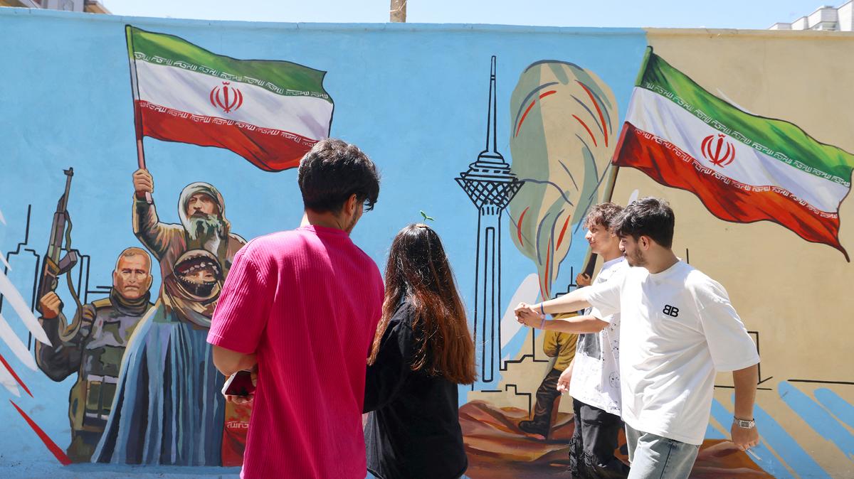 Iranians walk past an anti-US and anti-Israel mural painted on a wall in Tehran on May 10, 2026. The spokesman for the Iranian parliament's national security commission warned the United States on May 10 against any attacks on vessels in Persian Gulf waters.