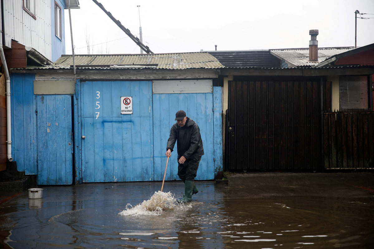 A local resident cleans the outside of his house of floodwater from the rain, which occurred during a weather front that led the Chilean authorities to declare a preventive state of emergency at the start of the week, in Arauco, Chile, July 16, 2026. REUTERS/Juan Gonzalez