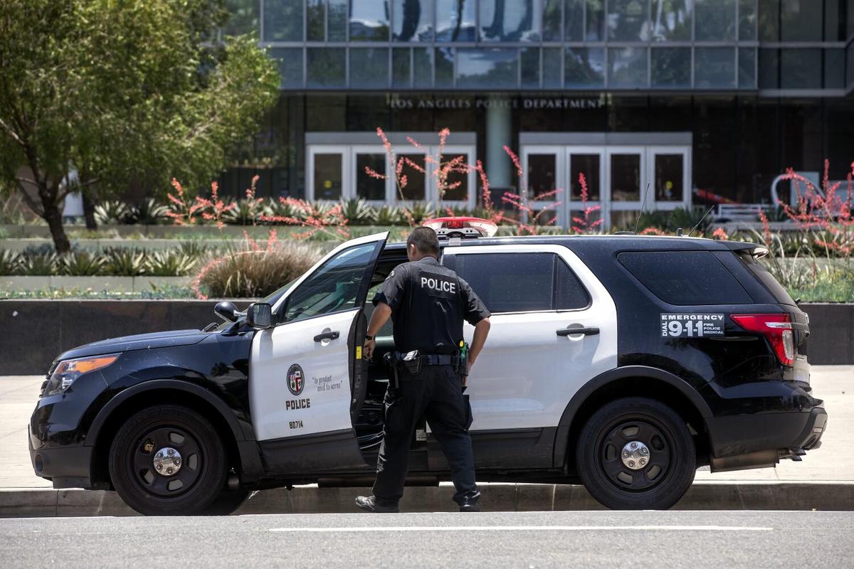A member of the Los Angeles Police Department gets into his patrol car parked in front of LAPD headquarters on First Street in downtown Los Angeles.