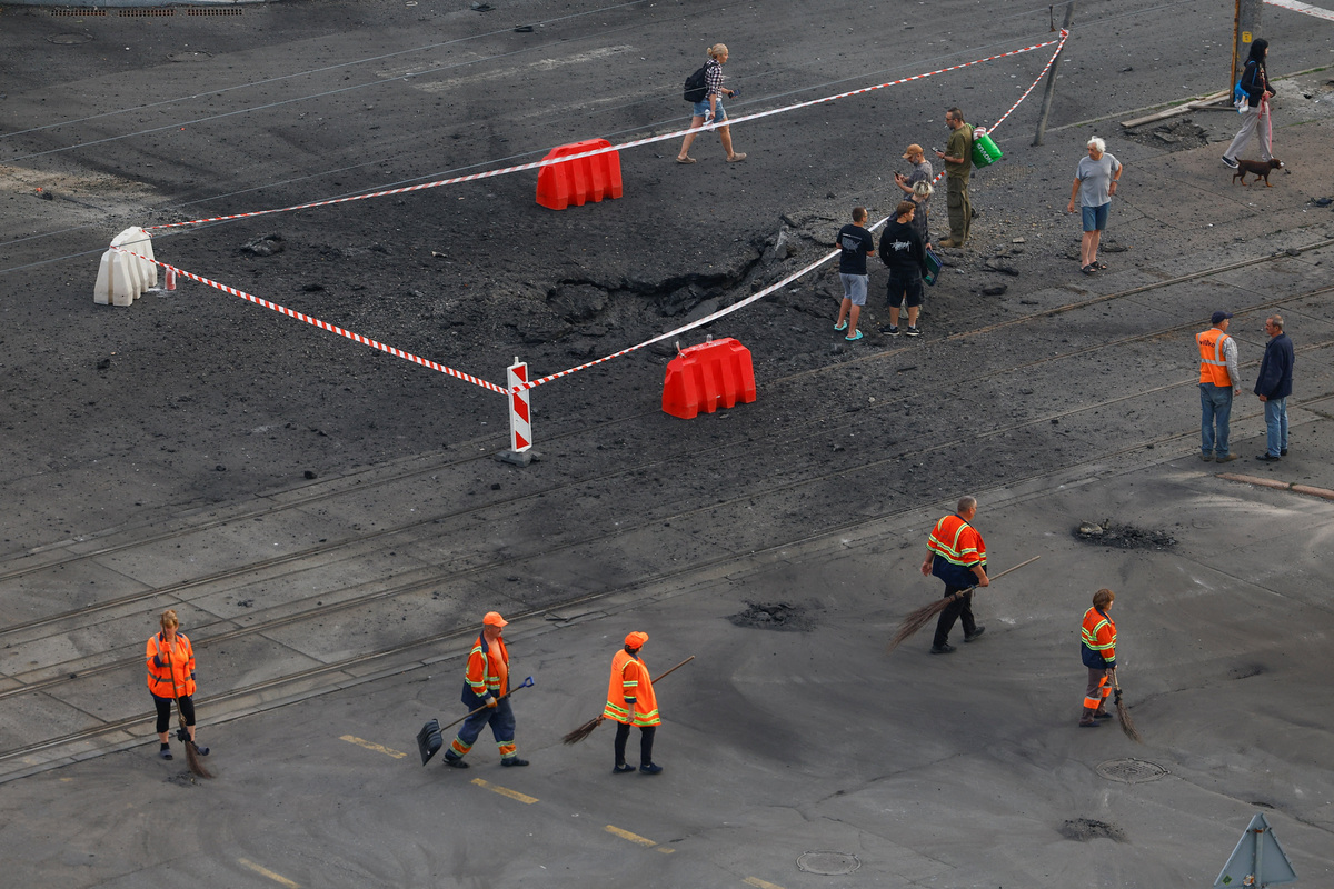Residents gather next to a crater that appeared after Russian missile strikes while municipal employees remove debris, amid Russia's attack on Ukraine, in Kyiv, Ukraine July 11, 2026. REUTERS/Valentyn Ogirenko