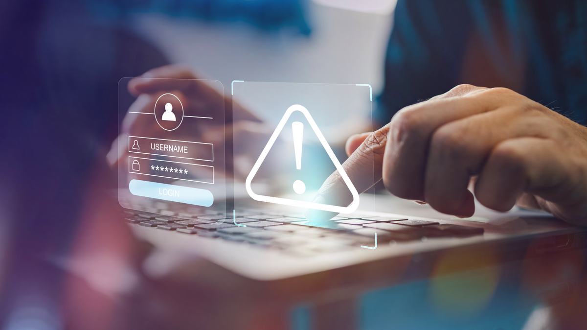 A stock image shows a hand using a laptop and a malware screen with phishing email, hack password and personal data. 