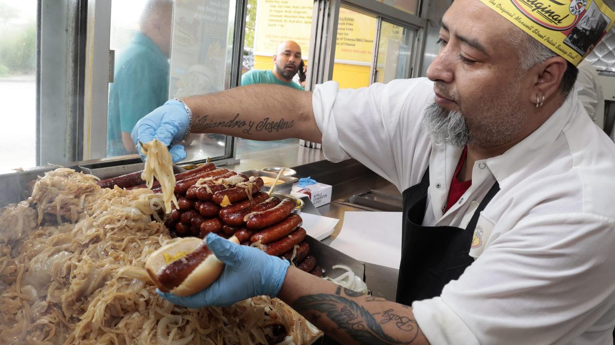 Isaias Trevino prepares a Polish sausage with sauerkraut for a customer at Jims Original at 1250 S. Union Ave. in Chicago, Aug. 9, 2023. (Antonio Perez/Chicago Tribune)