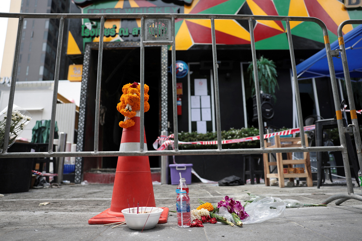 Flowers and offerings are placed outside Rong Beer Na Lat Phrao bar, the site of a deadly fire, to pay tribute to victims who lost their lives in the bar fire, the day after the incident, in Bangkok, Thailand, July 14, 2026. REUTERS/Chalinee Thirasupa