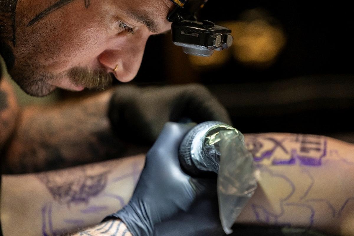 Randolph Torres tattoos the leg of Lexya Siebrands in Fort Morgan, Colorado, U.S., May 11, 2026.  REUTERS/Kevin Mohatt