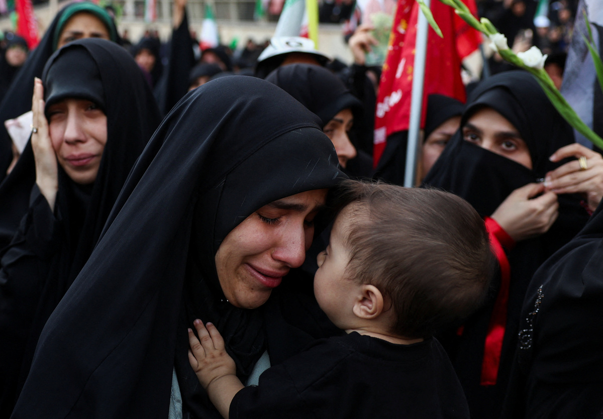 A woman mourns while carrying a child as people gather on the day of a public farewell ceremony to pay their respects to late Supreme Leader Ayatollah Ali Khamenei, who was killed on February 28 in Israeli and U.S. airstrikes, at the Imam Khomeini Grand Mosalla, in Tehran, Iran July 4, 2026.  Majid Asgaripour/WANA (West Asia News Agency) via REUTERS