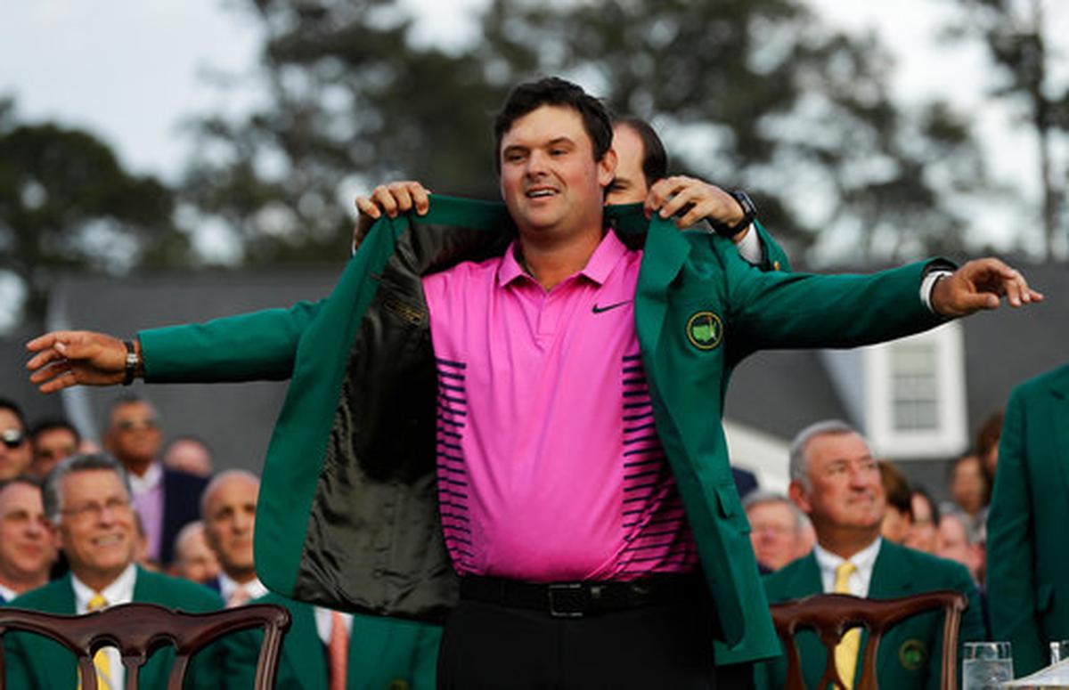Former Masters champion Sergio Garcia, right, of Spain, helps Patrick Reed with his green jacket after winning the Masters golf tournament Sunday, April 8, 2018, in Augusta, Ga.