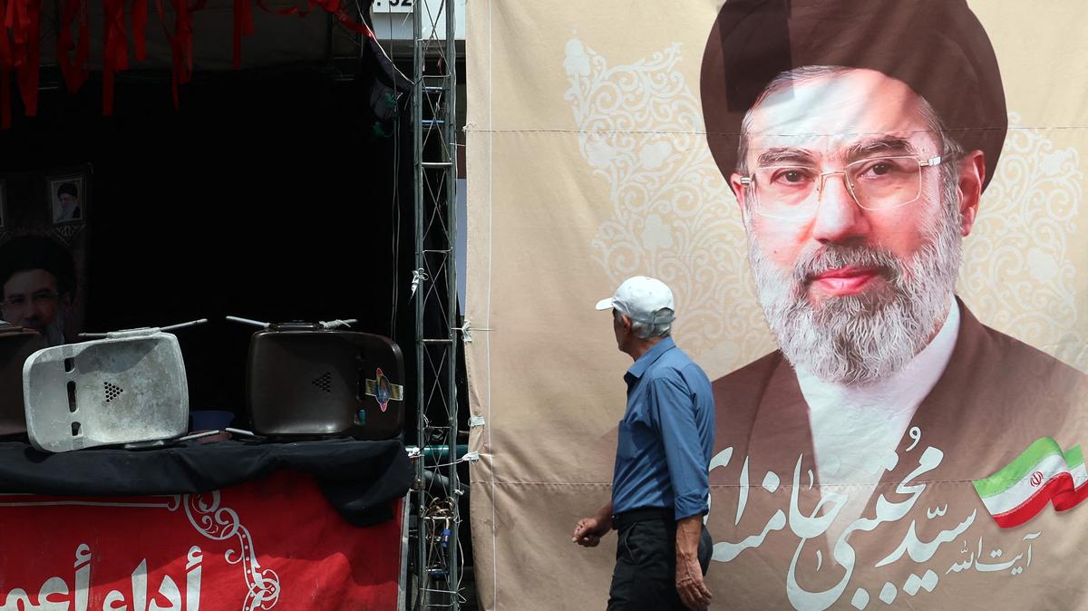 An Iranian man walks past a billboard carrying a picture of Iran's Supreme Leader Mojtaba Khamenei erected along a street in Tehran on May 28, 2026. (AFP/Getty Images/TNS)