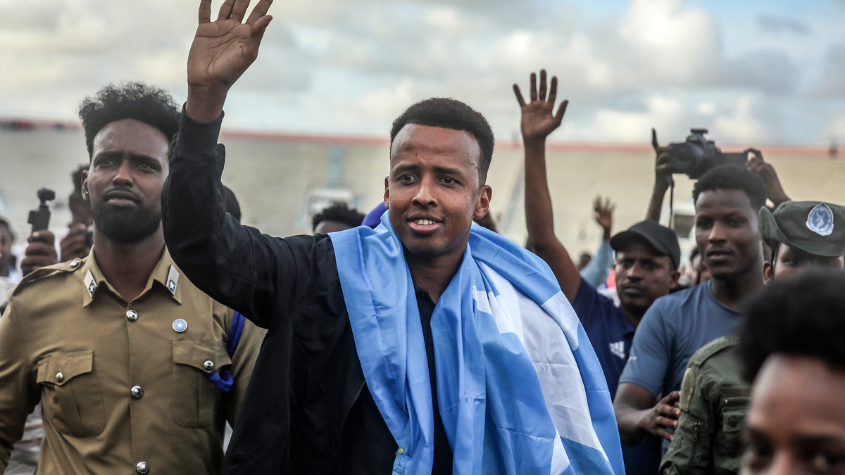 TOPSHOT-FBL-WC-2026-SOM-REFEREE-IMMIGRATION-DIPLOMACY. TOPSHOT - Somali international referee Omar Abdulkadir Artan waves to supporters while draped in the Somali flag as he is welcomed ahead of a solidarity football match after returning to Somalia in Mogadishu on June 10, 2026. Somali referee Omar Artan, who was denied entry to the United States for the World Cup, returned to a hero's welcome in Mogadishu and vowed to take part in the next tournament in 2030. Artan's rejection has sparked outrage at home.Artan, who in 2025 was named men's referee of the year by the Confederation of African Football (CAF), was barred from entering the US on Saturday after arriving at Miami International Airport. (Photo by Hassan Ali Elmi / AFP via Getty Images)
