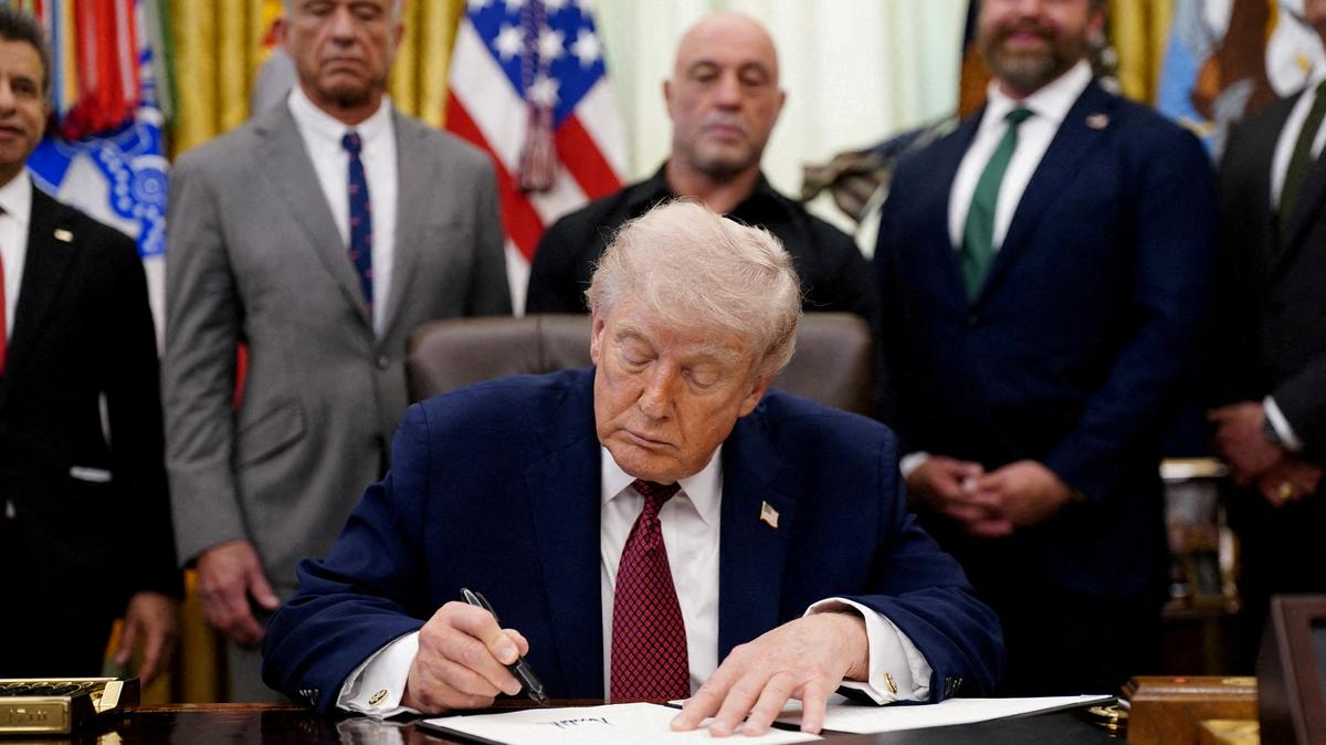 FILE PHOTO:  U.S. President Donald Trump signs an executive order encouraging more research into ibogaine, next to U.S. Health and Human Services (HHS) Secretary Robert F. Kennedy Jr., Joe Rogan, and Americans for Ibogaine CEO W. Bryan Hubbard, in the Oval Office of the White House in Washington, D.C., April 18, 2026. REUTERS/Nathan Howard/File Photo