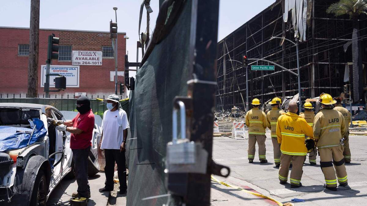Julio Reyes, left, works on a vehicle at the N&M Auto Repair located steps away from a smouldering cold storage facility in Boyle Heights on Thursday, June 25, 2026. (Photo by Drew A. Kelley, Press-Telegram/SCNG)