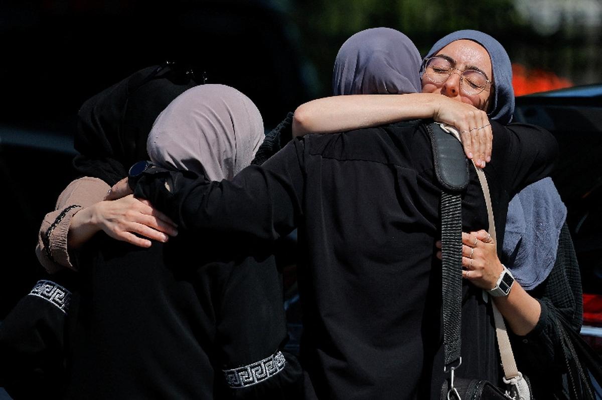 Women comfort each other outside the Islamic Centre of San Diego the morning following a shooting, in San Diego, California, U.S, May 19, 2026.  REUTERS/ Mike Blake