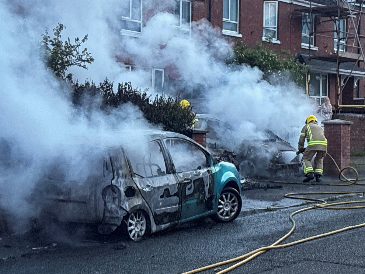 Firefighters work to extinguish a fire in three cars parked on the street at Tigers Bay, during a protest after a knife attack on June 8 left a man seriously injured and prompted police to declare a critical incident, in Belfast, Northern Ireland, June 9, 2026. REUTERS/Isabel Infantes