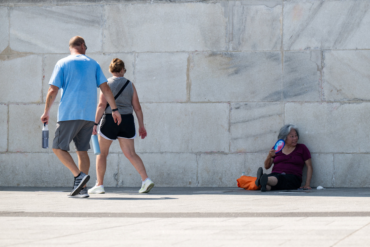 A woman sits in the shade and fans herself at the base of the Washington Monument due to excessive heat in Washington, D.C., U.S., July 1, 2026. REUTERS/Annabelle Gordon
