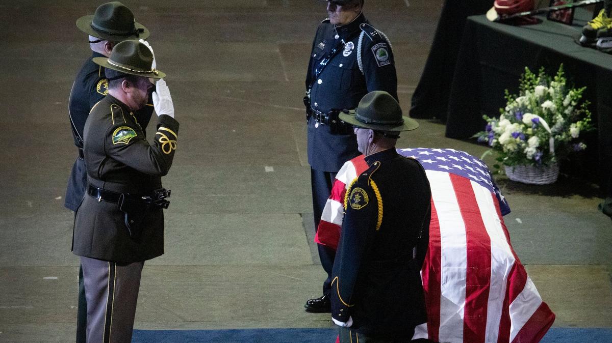 Law enforcement officers salute the casket of Everett Police Officer Dan Rocha at a memorial service at Angel of the Winds Arena, Monday, April 4, 2022 in downtown Everett, Wash. Rocha was fatally shot while confronting a suspect in a parking lot in late March.