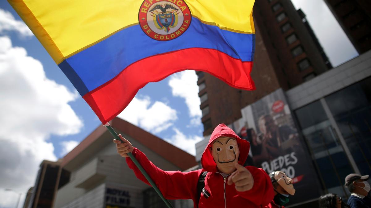 Un hombre enmascarado ondea una bandera colombiana durante una marcha contra el gobierno en Bogotá, Colombia, el miércoles 19 de mayo de 2021. Los colombianos han salido a las calles durante semanas en todo el país después de que el gobierno propuso aumentos de impuestos a los servicios públicos, combustible, salarios y pensiones. (AP Foto/Ivan Valencia)