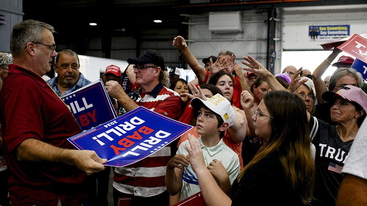 Placards are handed out before a rally in Potterville, Mich., Aug. 29. Donald Trump has pledged to eliminate all of the Biden administration’s regulations aimed at cutting carbon emissions from automobile tailpipes, power plants and oil and gas wells. 