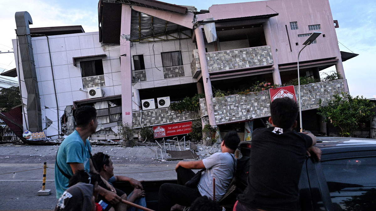 Passengers on the cargo bed of a pickup truck look at a damaged building a day after the magnitude 7.8 quake in General Santos, southern Philippines, June 9, 2026. REUTERS/Noel Celis     TPX IMAGES OF THE DAY