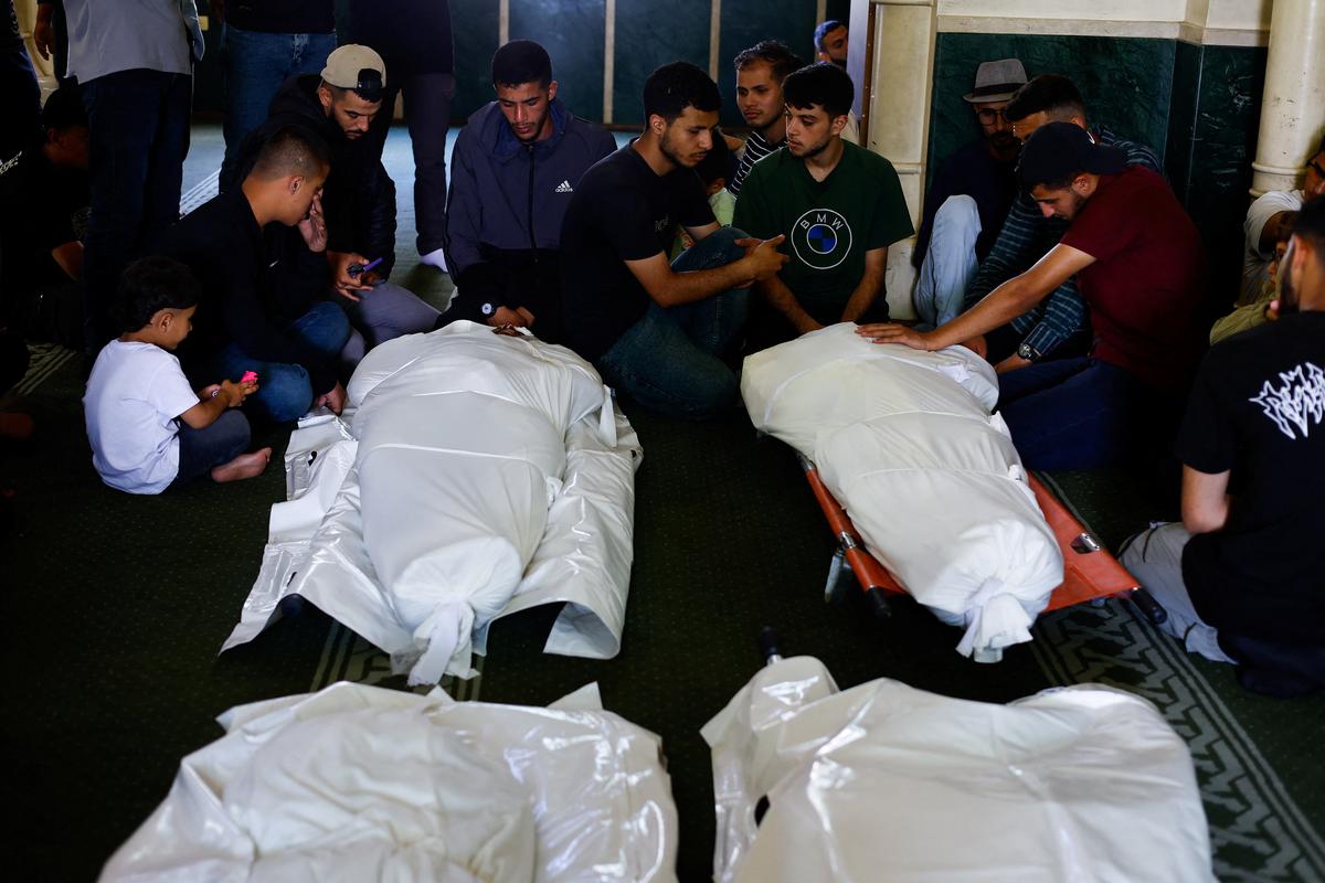 Mourners sit next to bodies identified as Hamas' military wing commander Mohammad Odeh, who was killed in an Israeli strike on Tuesday, and his wife and children, during a funeral, in Gaza City, May 27, 2026. REUTERS/Mahmoud Issa