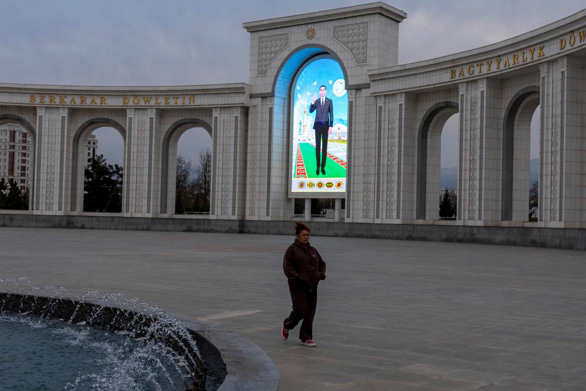 A woman walks past an illuminated portrait of Turkmen President Serdar Berdymukhamedov in a park in Ashgabat, Turkmenistan, March 20, 2026. REUTERS/Umit Bektas