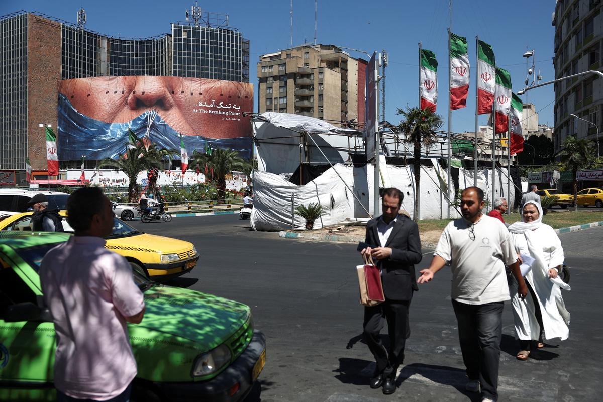 People walk past an anti-U.S. billboard depicting U.S. President Donald Trump and the Strait of Hormuz, in Tehran, Iran, May 26, 2026. Majid Asgaripour/WANA (West Asia News Agency) via REUTERS