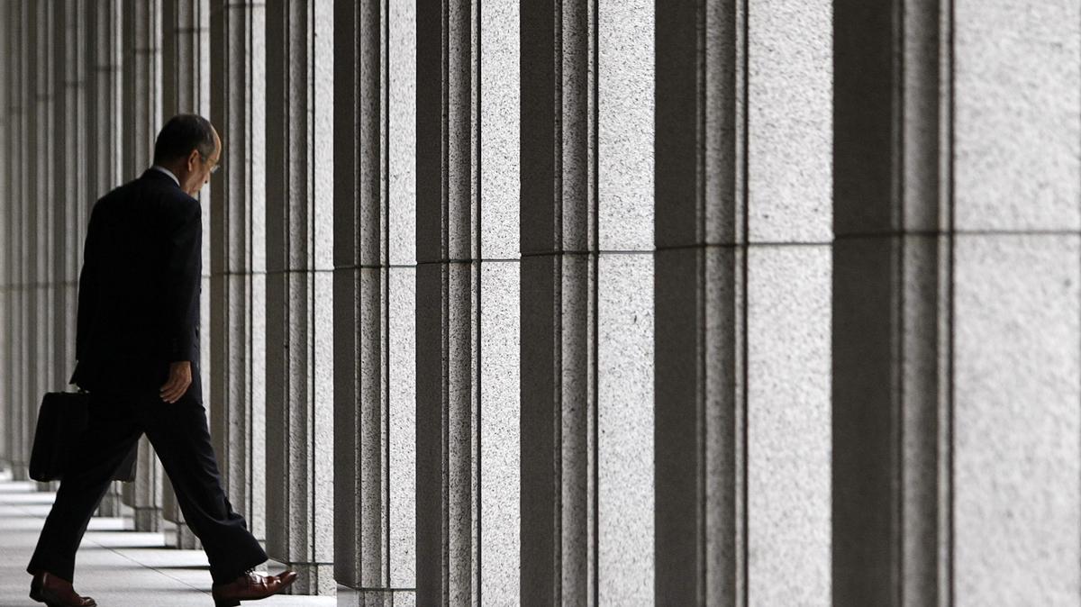 A businessman walks out from an office building near the Bank of Japan in Tokyo June 16, 2009. The Bank of Japan upgraded its economic assessment on Tuesday, as rising exports and output raise expectations the worst of the recession is over, but its cautious tone suggested it was in no hurry to end extraordinary policy measures.   REUTERS/Toru Hanai (JAPAN BUSINESS)