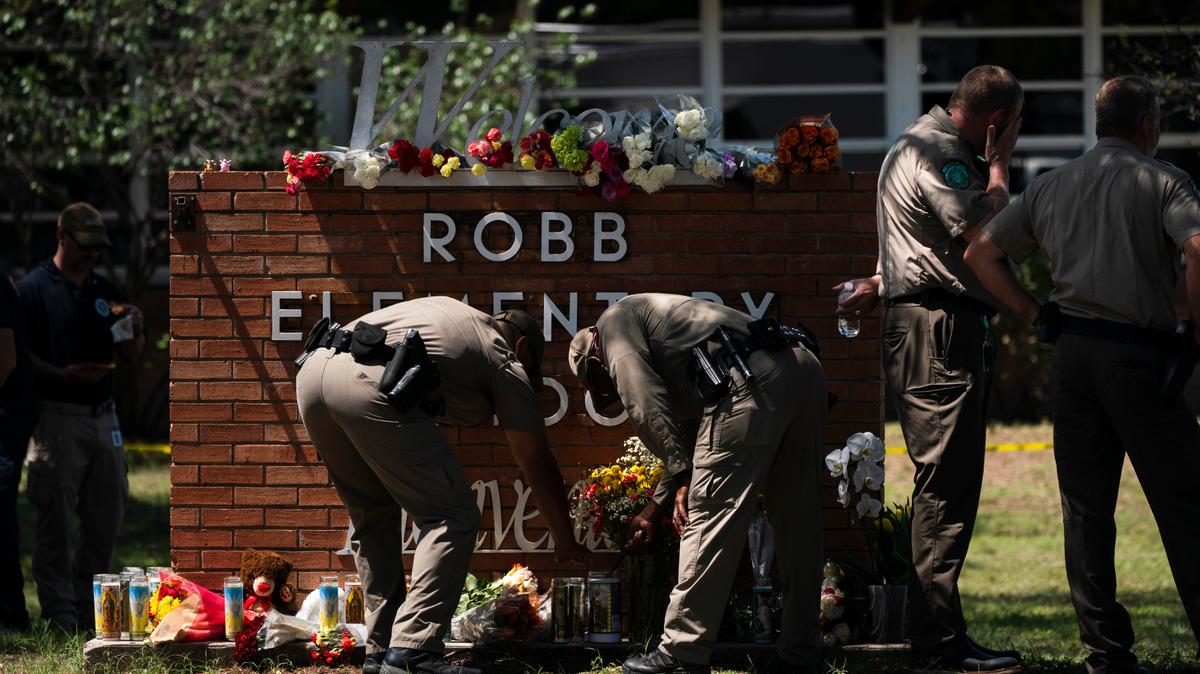 Two Texas Troopers light a candle at Robb Elementary School in Uvalde, Texas, on Wednesday.