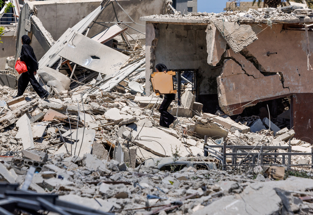 Women hold belongings as they walk among the rubble of a neighborhood completely destroyed by an Israeli airstrike, following the U.S.–Iran deal, in Qlailieh, Tyre district, Lebanon, June 18, 2026. REUTERS/Zohra Bensemra