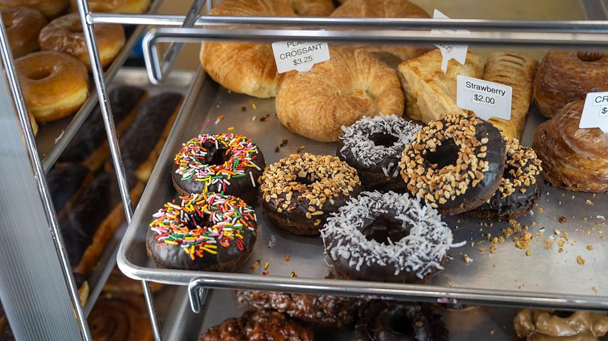 Assorted donuts with chocolate icing, sprinkles, coconut, and nuts displayed in a bakery case, Lafayette, California, April 22, 2026. (Photo by Smith Collection/Gado/Getty Images). 