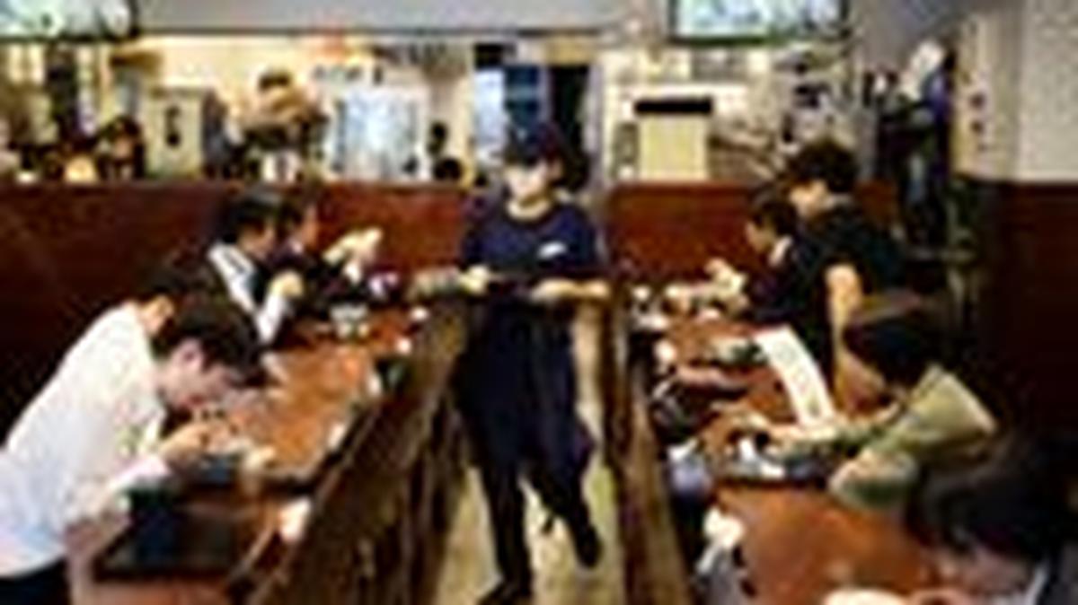 A staff member serves 'gyudon' beef bowl to customers inside Yoshinoya restaurant in Tokyo, Japan May 19, 2025.  REUTERS/Issei Kato
