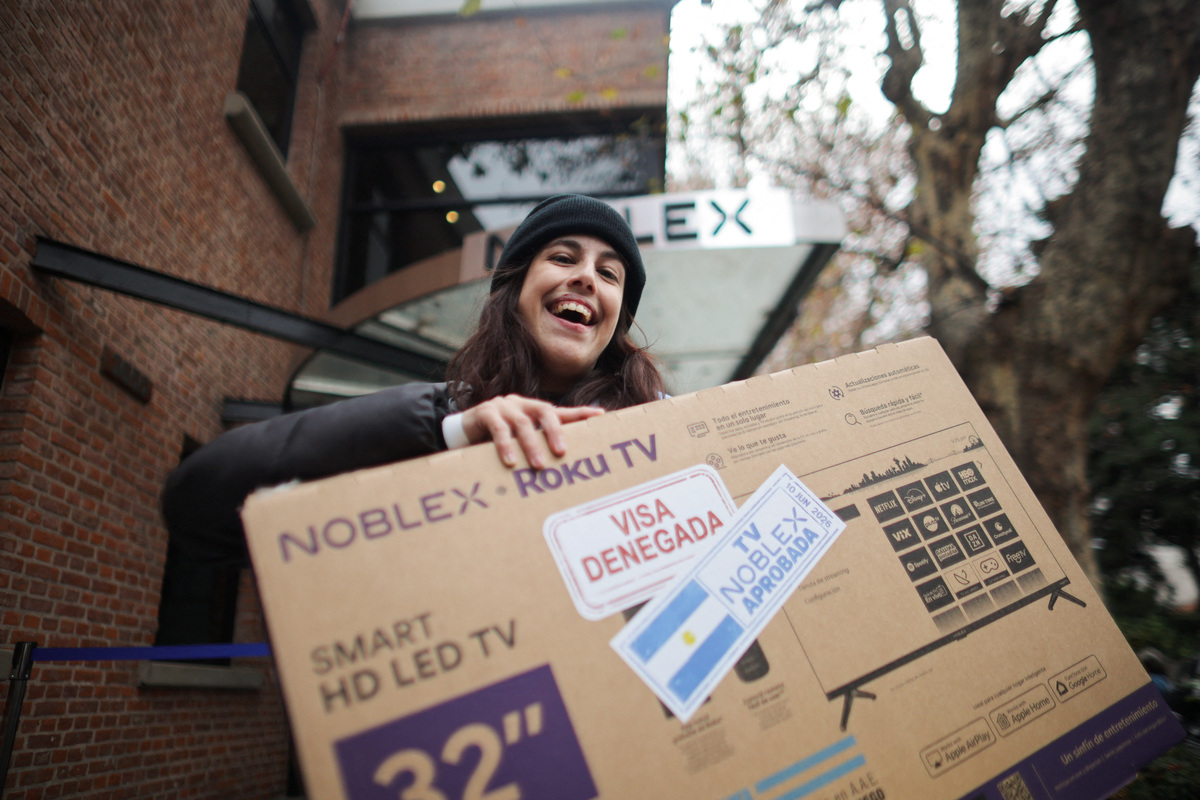 A woman carries a television set she received for free after showing her U.S. visa denial during a promotion by television manufacturer Noblex for people unable to travel to the World Cup due to visa rejections, in Buenos Aires, Argentina, June 10, 2026. The stickers on the television box read "visa denied" and "TV Noblex approved". REUTERS/ Tomas Cuesta
