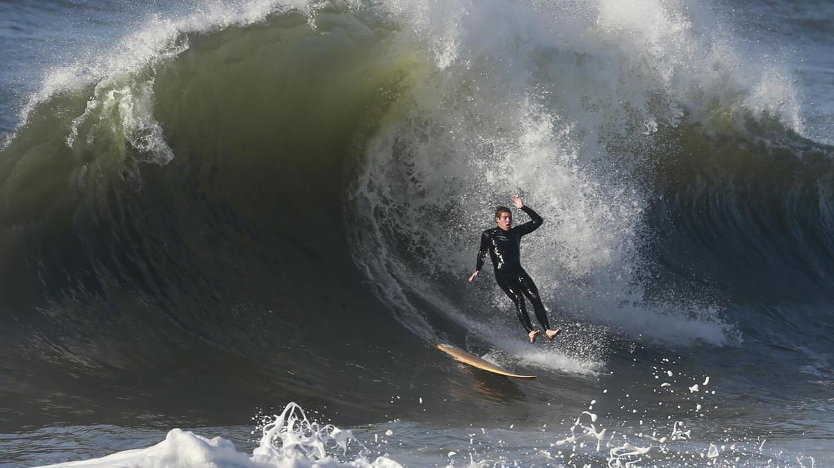 A surfer goes over the falls on a big wave in Seal Beach during stormy weather. (Allen J. Schaben/Los Angeles Times/TNS)