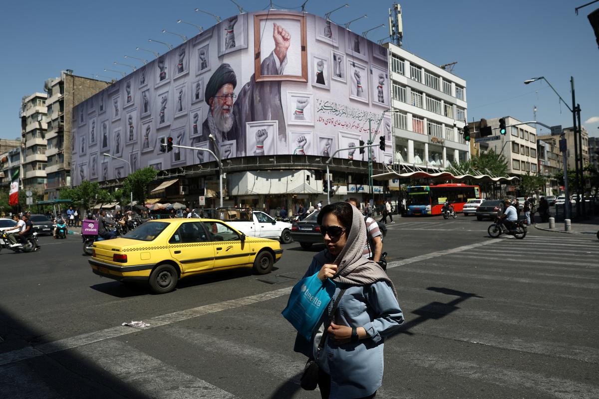 A woman walks near a billboard featuring an image of the late Supreme Leader of Iran, Ayatollah Ali Khamenei, in Tehran, Iran, May 11, 2026. Majid Asgaripour/WANA (West Asia News Agency) via REUTERS